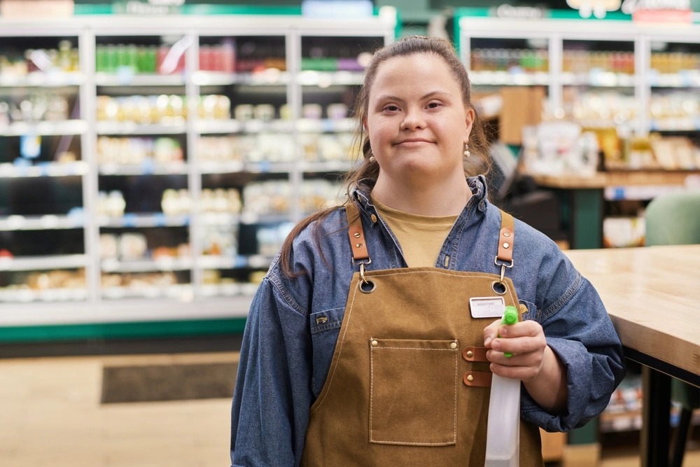 Down syndrome disabled girl working as a cleaner in a store