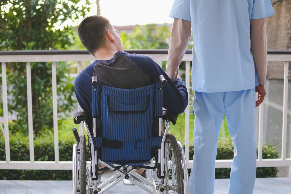 Nurse with disabled boy on wheelchair in balcony enjoying view