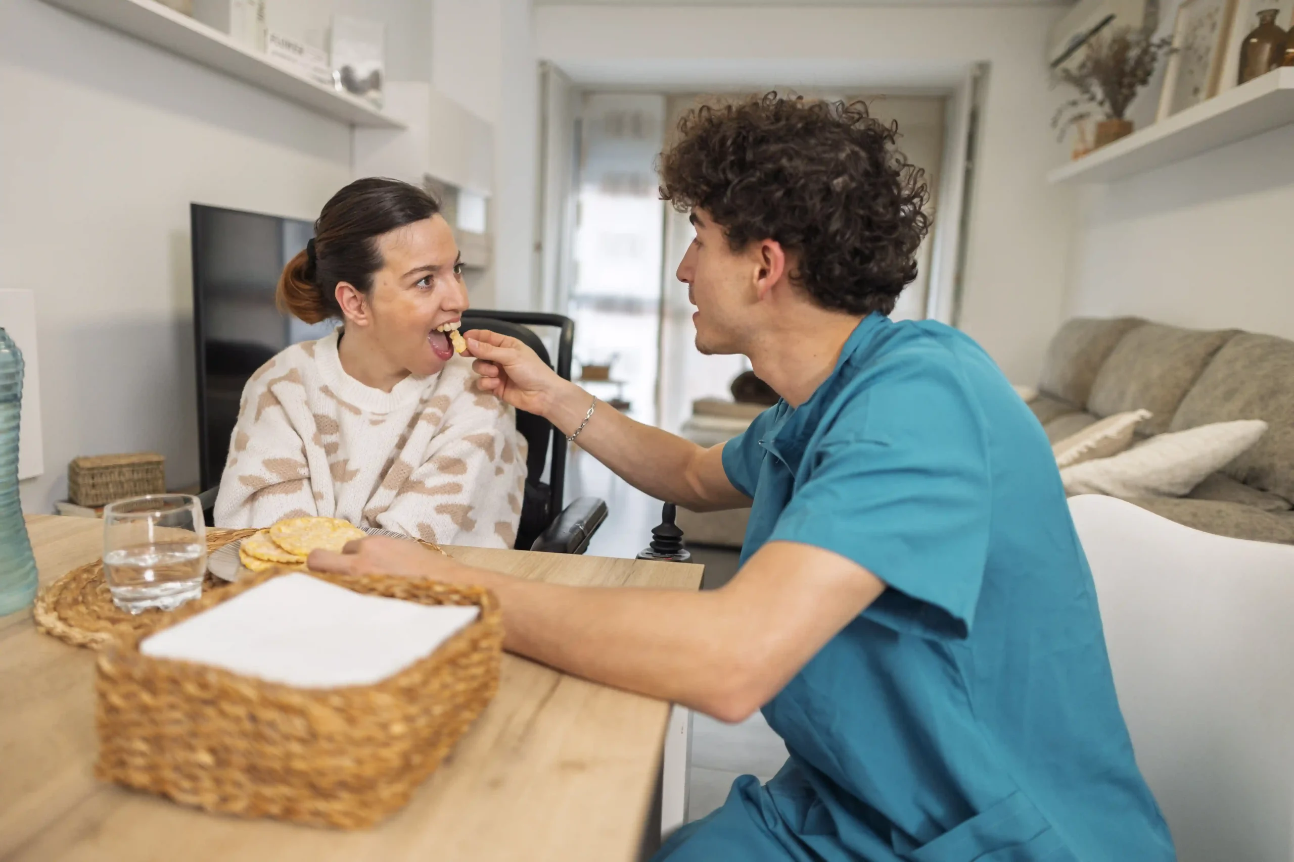 Nurse feeding a disabled women on wheelchair with downsyndrome