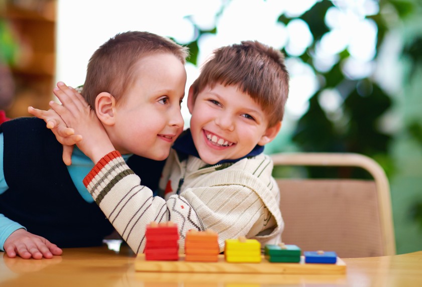 Young brother hugging disabled down syndrome brother and smiling